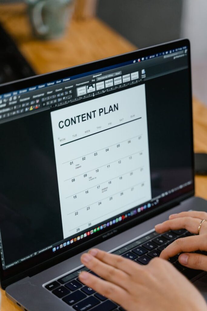 pexels-photo-7679733 Close-up of hands typing on a laptop displaying a content plan document, ideal for business or marketing content.